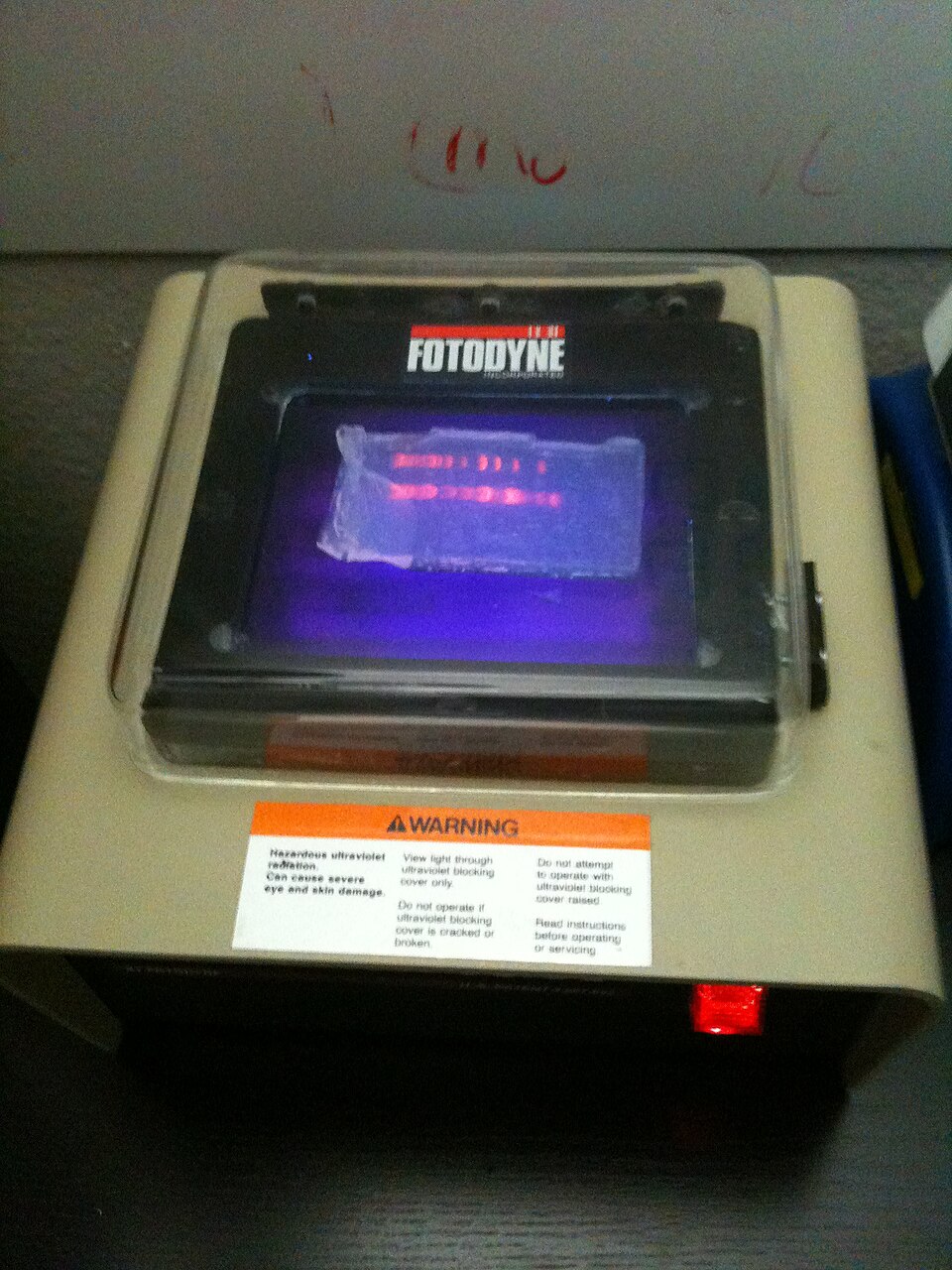 A real agarose gel under UV light, showing a DNA ladder lane and restriction digest lanes with orange-glowing bands